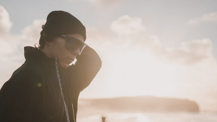 Une personne portant Smith , debout face à l'océan au moment du coucher du soleil. 