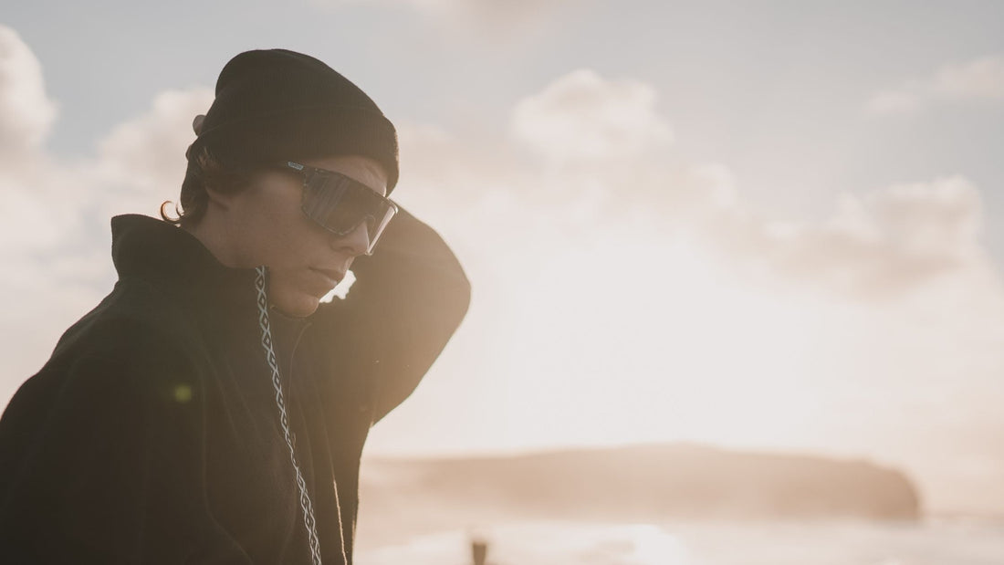 Person wearing Smith sunglasses, standing in front of the ocean while the sun sets. 