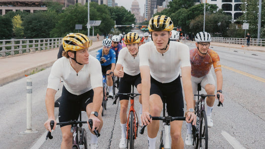 A group of Breakfast Club Austin members ride their bikes down an urban street.
