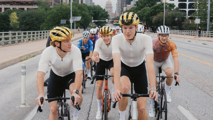A group of Breakfast Club Austin members ride their bikes down an urban street.