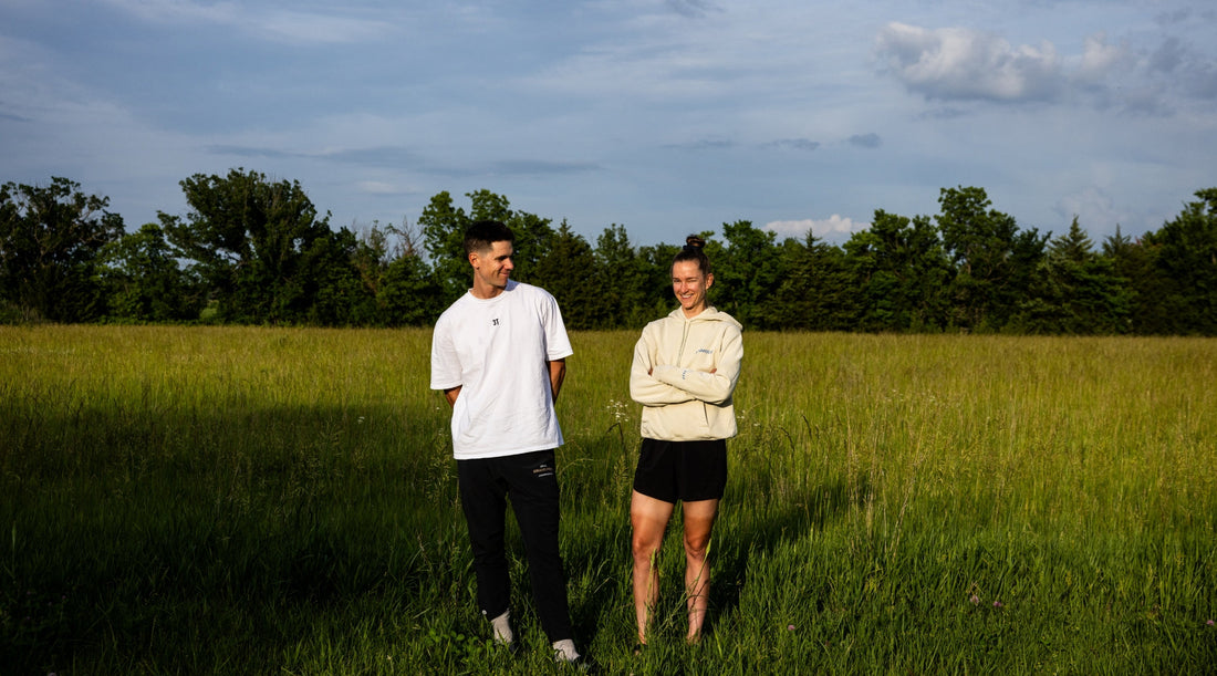 Lespy and Haley smile at each with blue sky and green grass in the background.