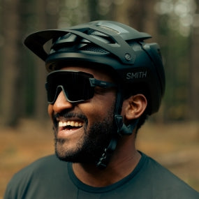 Person wearing a helmet and sunglasses in a forest setting