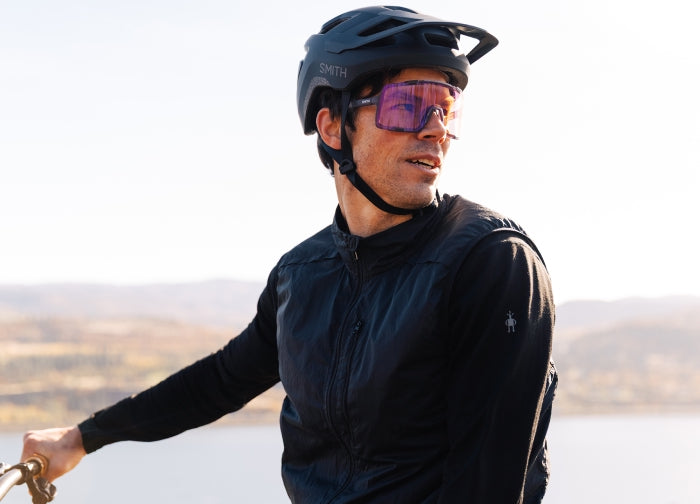 Person wearing the Smith Pilot helmet and Syncline sunglasses with a white background.