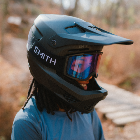 Person wearing a black Smith Hardline Mips helmet with Rhythm MTB goggles outdoors