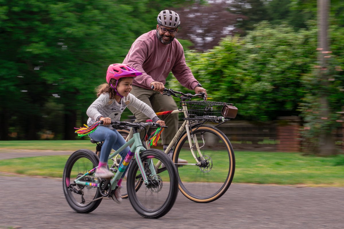 Father and daughter riding bikes around a park in their cool Smith helmets